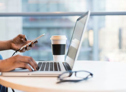 Someone working from a laptop and phone, accessing their tools from anywhere