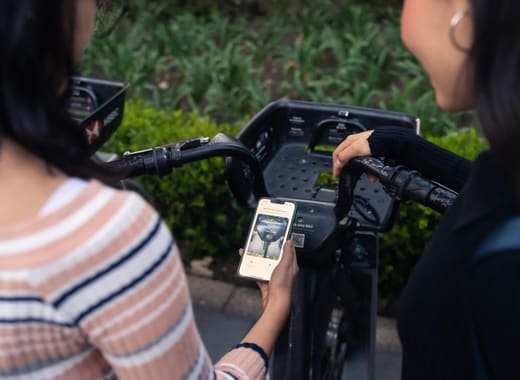 Two people scanning a QR code to unlock a shared bike